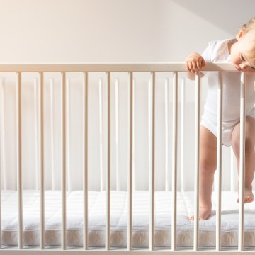Baby on the side of a crib railing